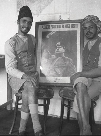 Haybi and an Arab cook pose with a poster of Mussolini. 