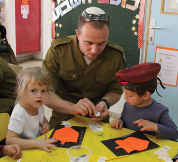 An Israeli soldier going through the conversion process visits a kindergarten in Efrat to learn about Hanukkah, November 2013. (Photo by Gershon Elinson/FLASH90.)