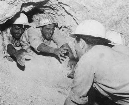 Excavation crews reach out to each other after tunneling through the rock as part of the National Water Carrier, 1960s, which carried billions of gallons of water to the Negev. (Courtesy of Daniel Rosenblum/Mekorot.)