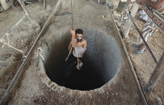 A Palestinian man is lowered into a smuggling tunnel beneath the Gaza-Egypt border, in the southern Gaza Strip, September 2013. (Photo by Mahmud Hams/AFP/Getty Images.) 
