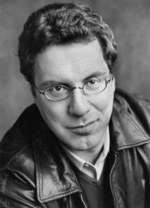 Black and white image of a man wearing glasses and a leather jacket. 