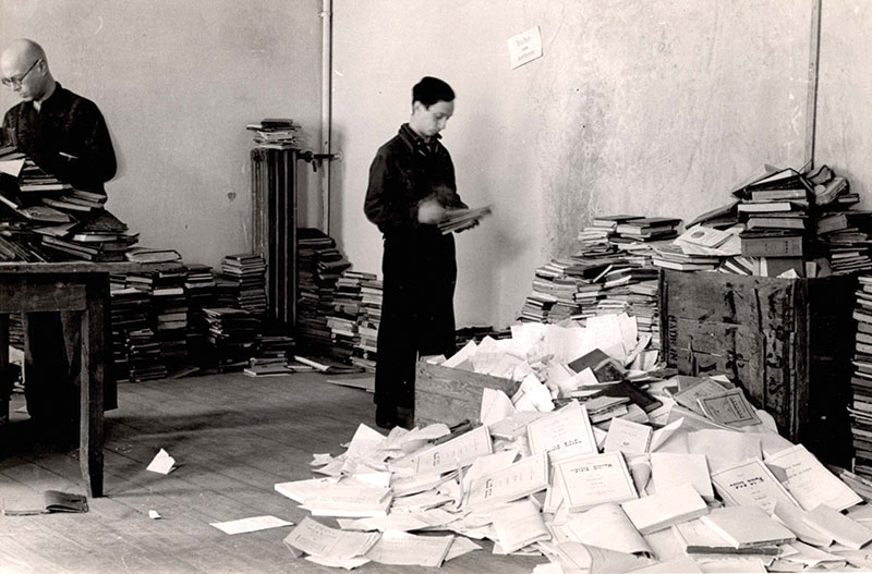 Photo of man sorting through piles of confiscated books