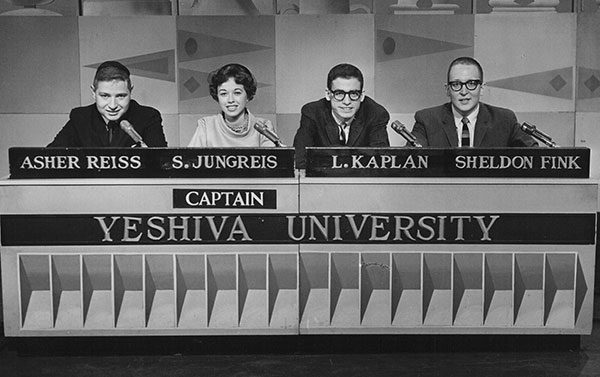 Four students seated at a desk for a quiz show